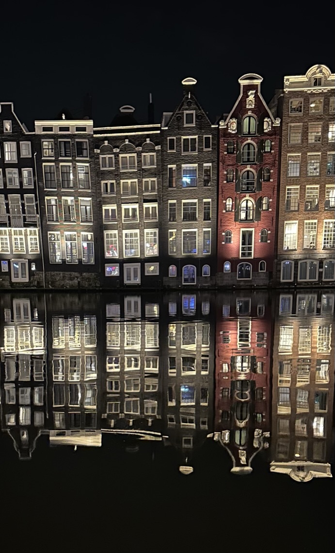Amsterdam canal houses reflected in dark water at night