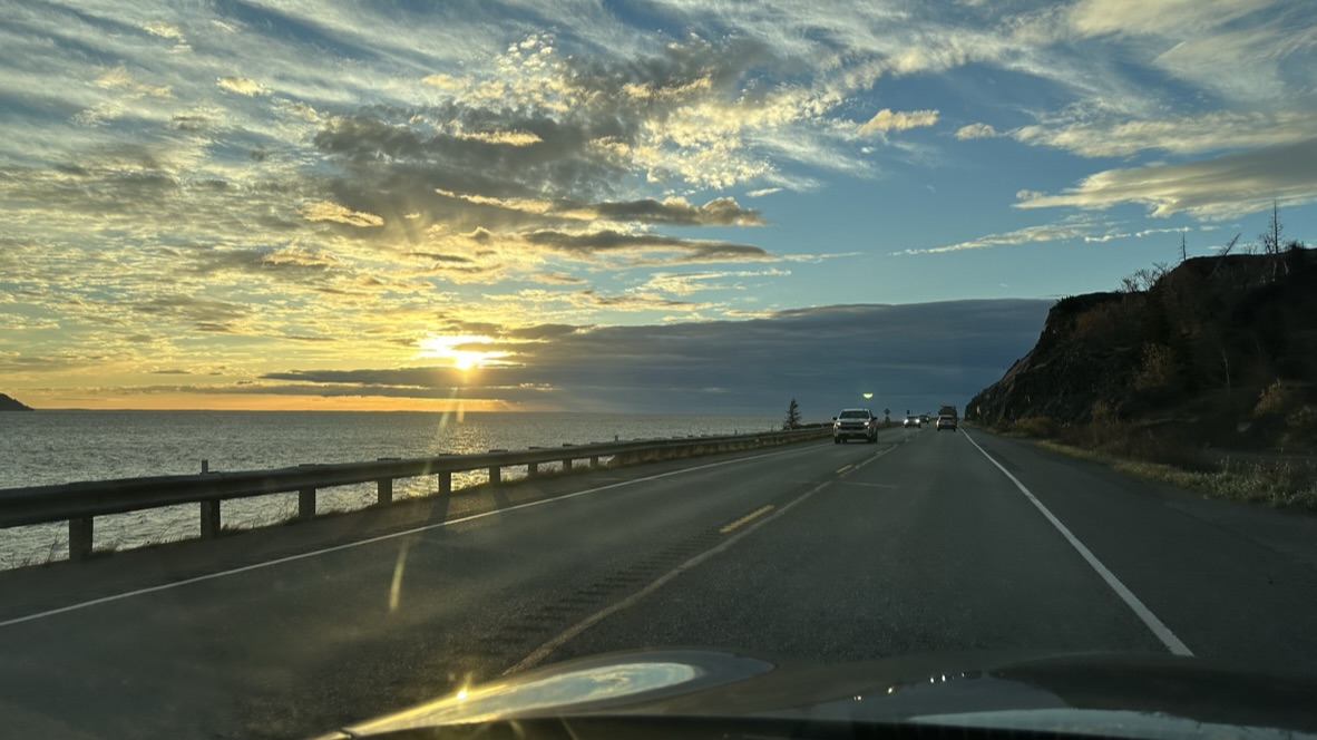 A coastal highway beneath a dramatic sunset sky